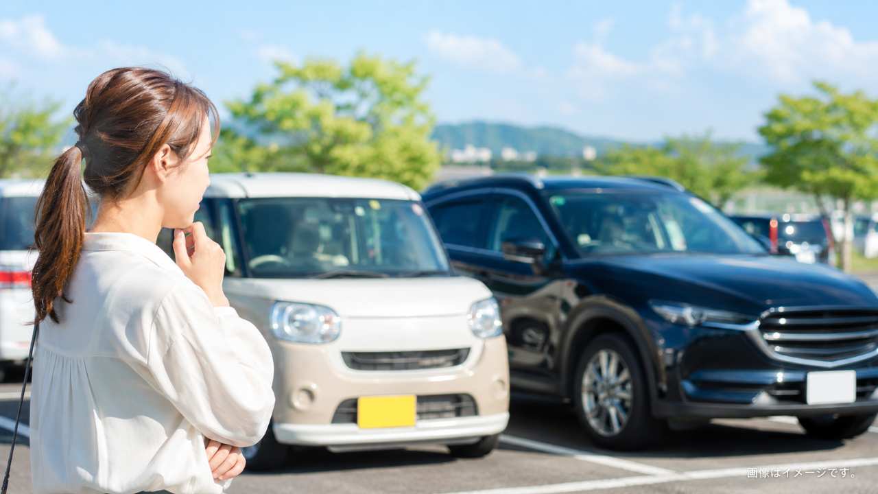 軽自動車とSUVが並ぶ駐車場で、売却タイミングを考えるイメージの写真風画像